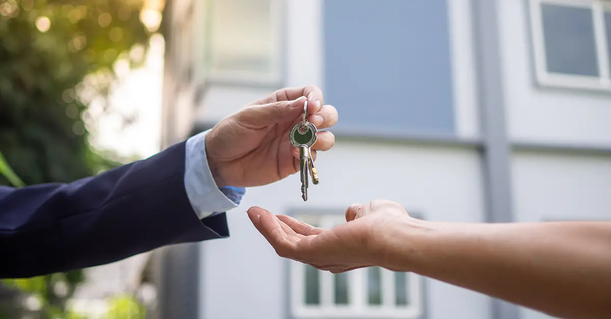 Photo of a landlord handing their new tenant the keys to their new rental home. Photo by Adobe Stock.